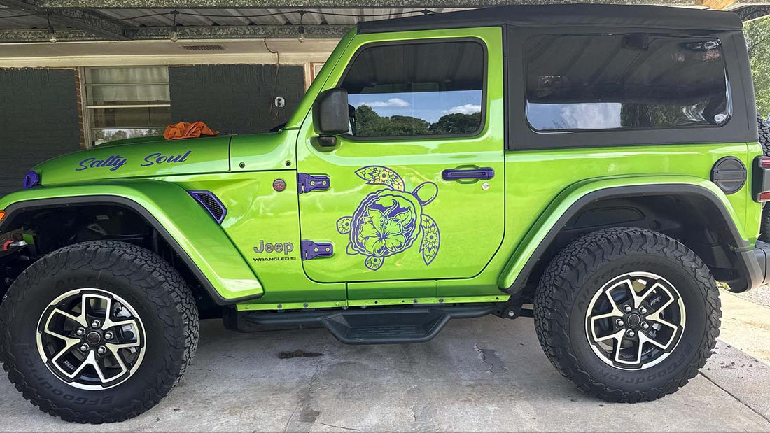 Jeep Wrangler on a wooded off-road trail showing decals on the hood, fender and lower body panels