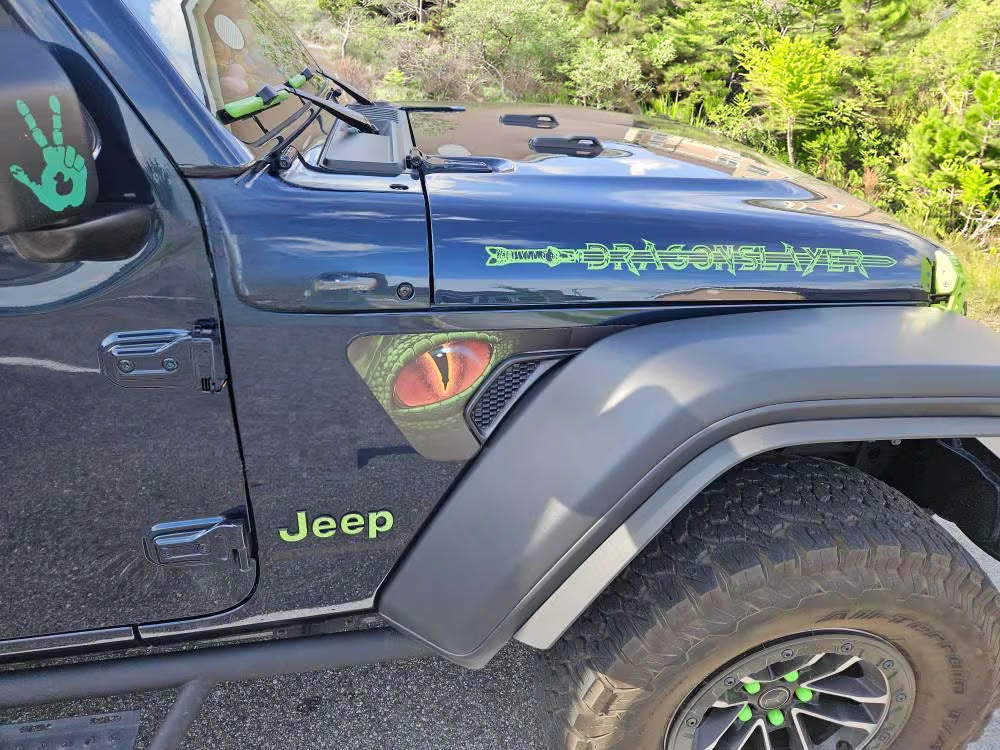 Black Jeep Wrangler with green Dragonslayer hood decal and custom graphics on the trail