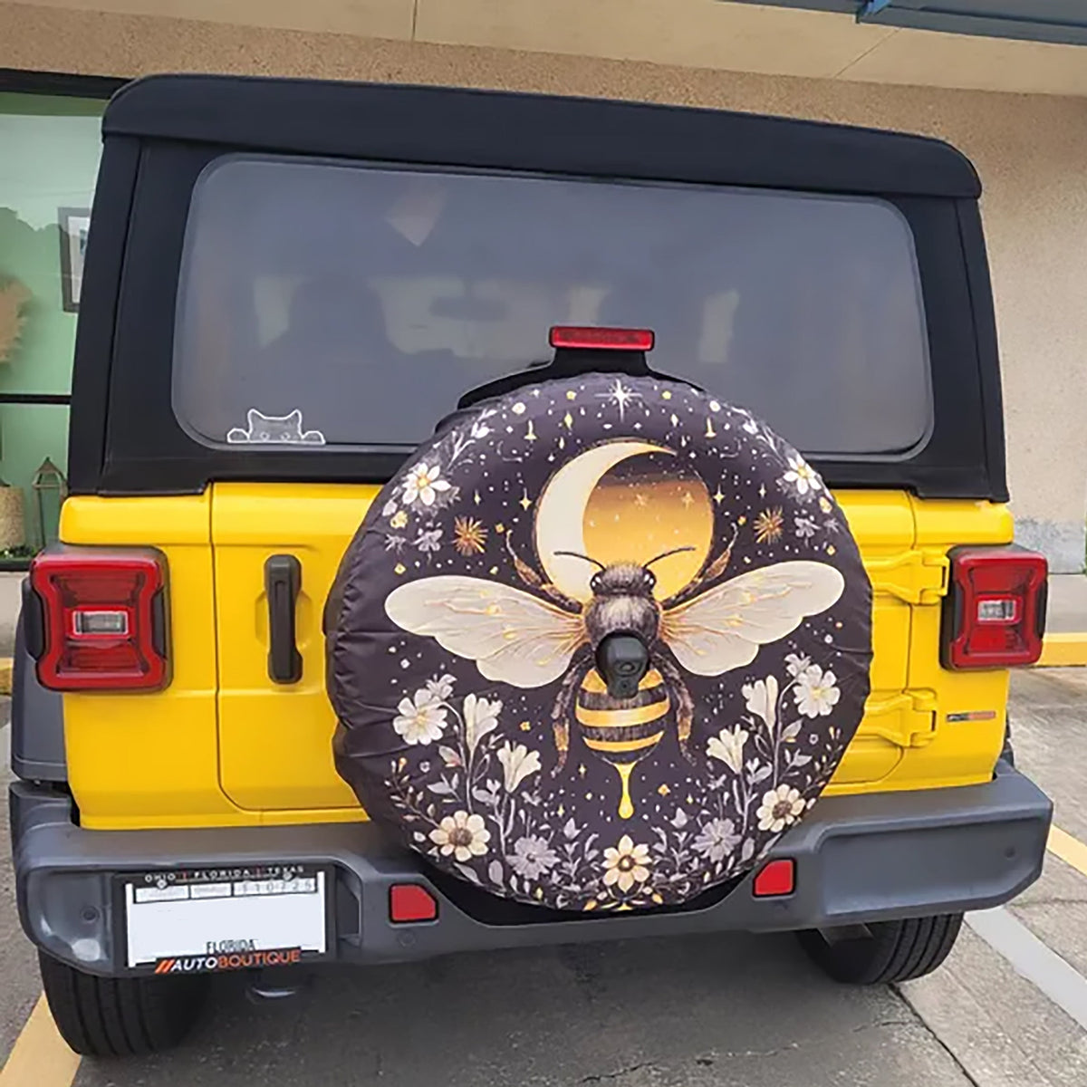 Celestial bee and moon spare tire cover with backup camera hole on a yellow Jeep Wrangler