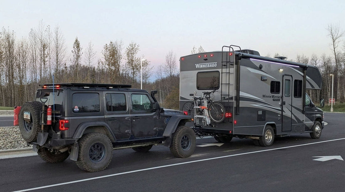 Jeep Wrangler being flat-towed on a highway behind a motorhome