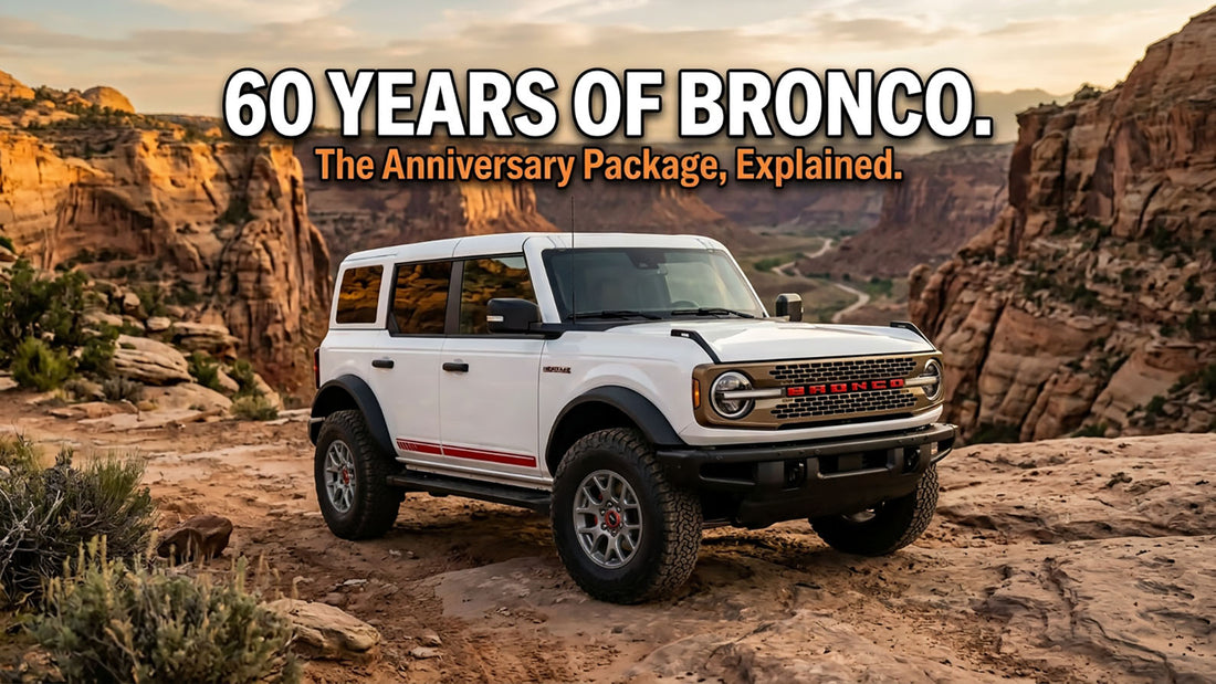 A white four-door Ford Bronco with a warm alloy grille, red BRONCO lettering, a red body-side stripe, and gray wheels, parked on a canyon overlook at sunset