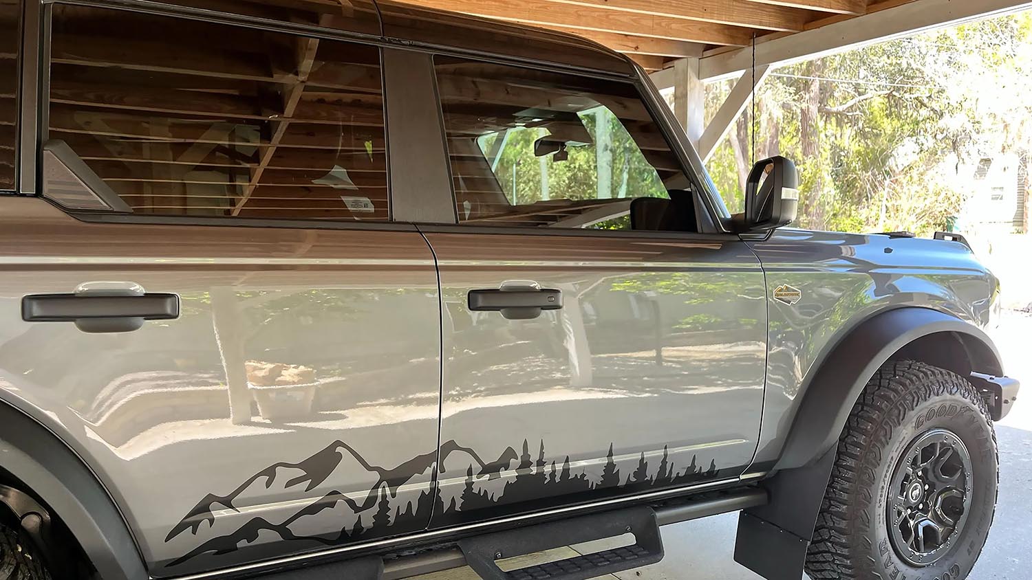 Gray 4-door Ford Bronco with a black mountain and pine forest side panel vinyl graphic along the lower doors