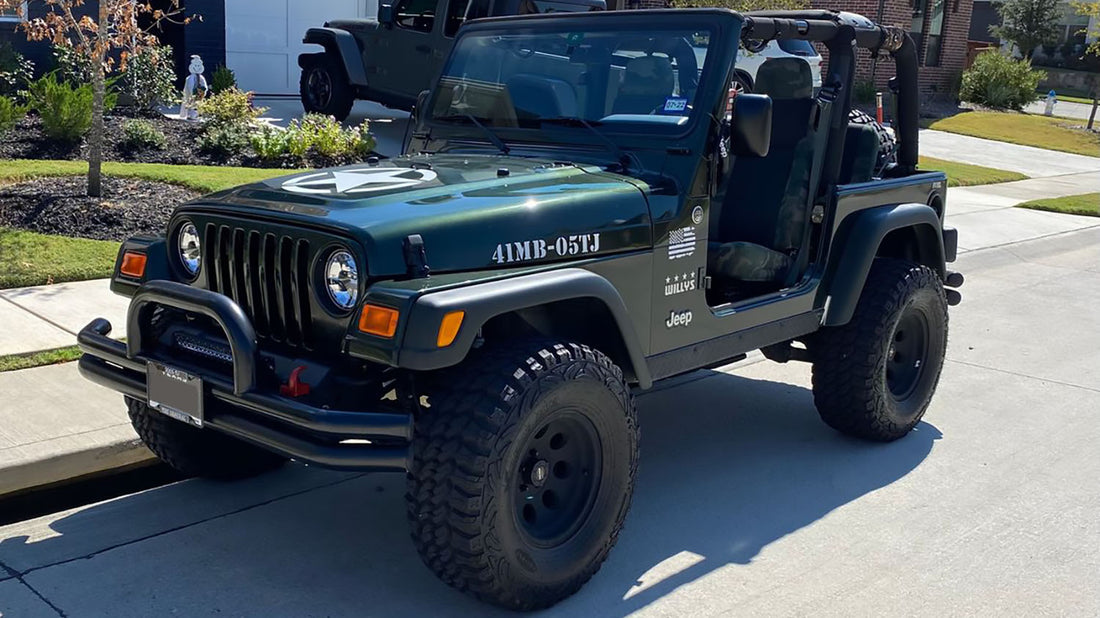 Dark green Jeep Wrangler TJ parked in a driveway with a white military star decal on the hood, 41MB-05TJ hood lettering, and a Willys fender decal