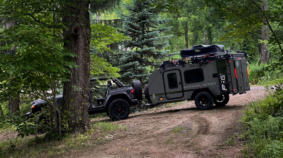 A Jeep Wrangler loaded as an overland rig for a long-haul trip, set up to tow an off-road trailer with its own spare