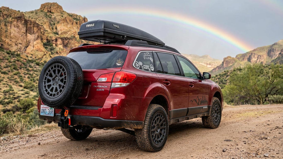 A Subaru Outback set up for overlanding with a hitch-mounted external full-size spare tire carrier at the rear