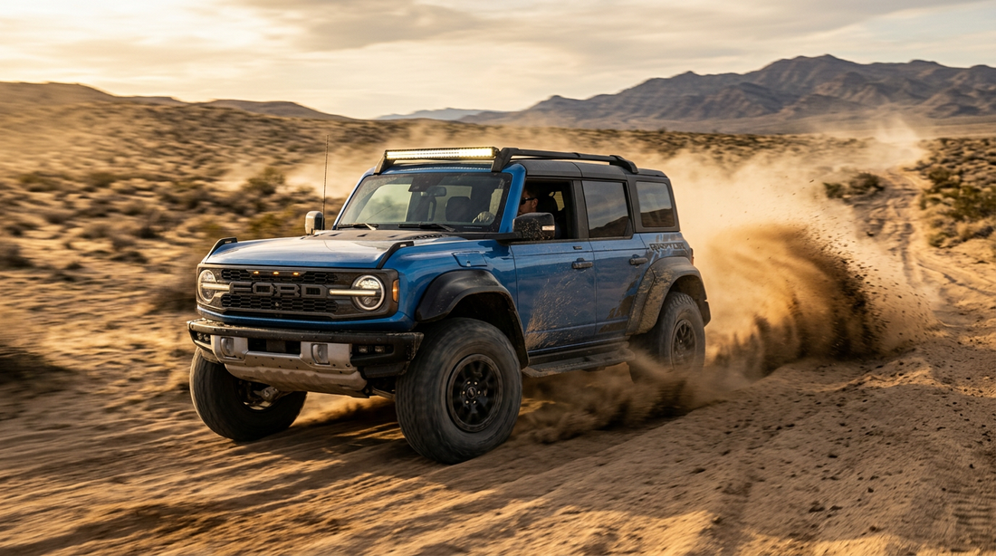 A Ford Bronco Raptor racing across the desert and kicking up sand at golden hour