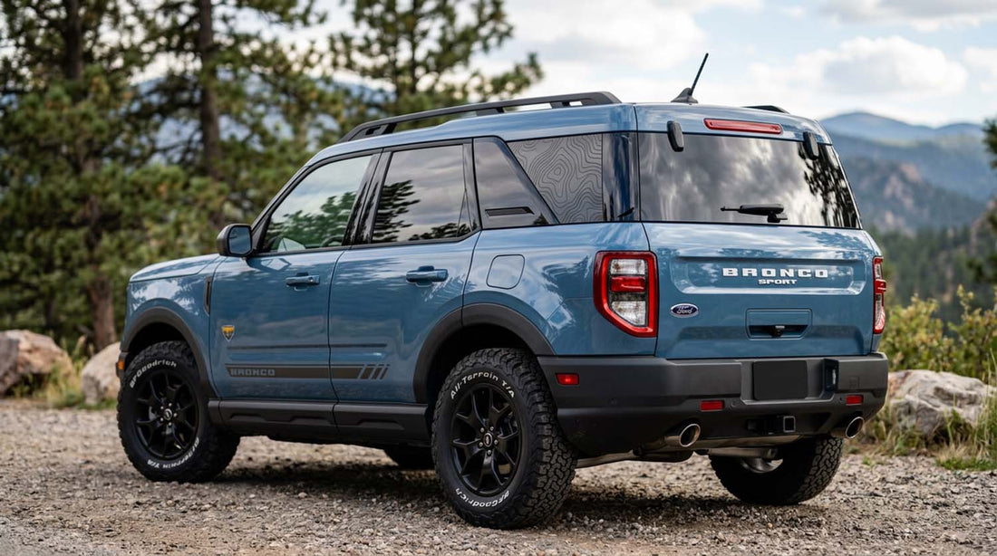 Blue Ford Bronco Sport with a topographic pattern rear quarter window decal and a BRONCO lower door graphic parked on a mountain trail
