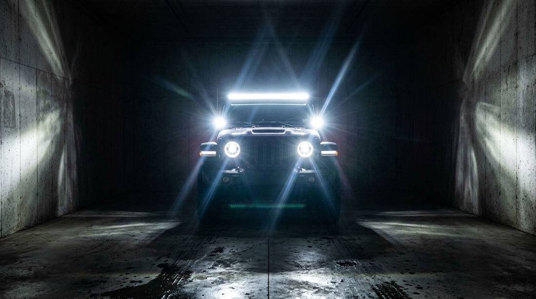 Jeep in a dark garage with headlights, light bar, and ditch lights on, showing beam placement for aiming