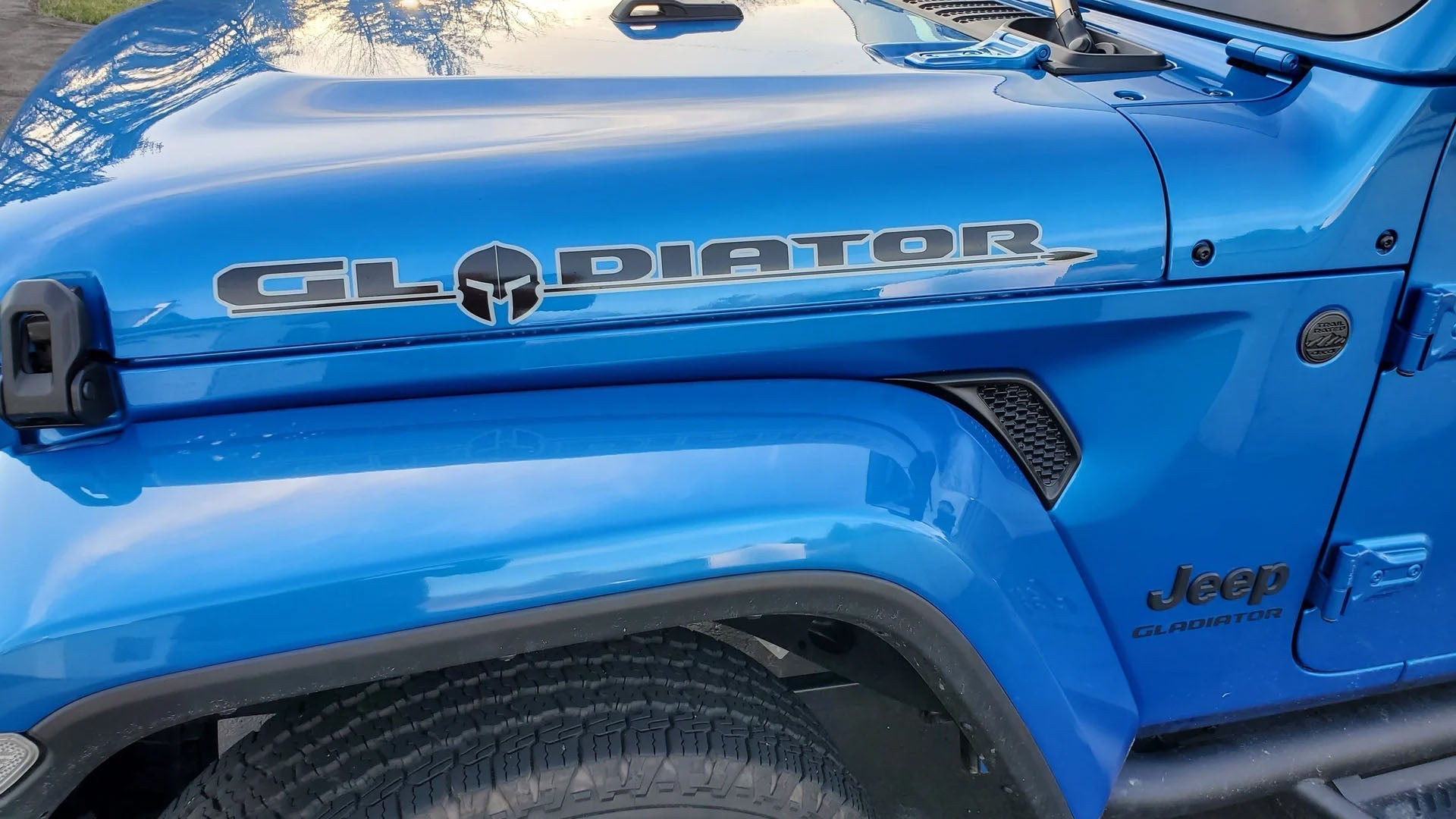 Hydro Blue Jeep Gladiator with a side hood decal on the trail