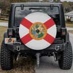 Florida state flag spare tire cover on black Jeep Wrangler with Graffix plate featuring red cross and state seal