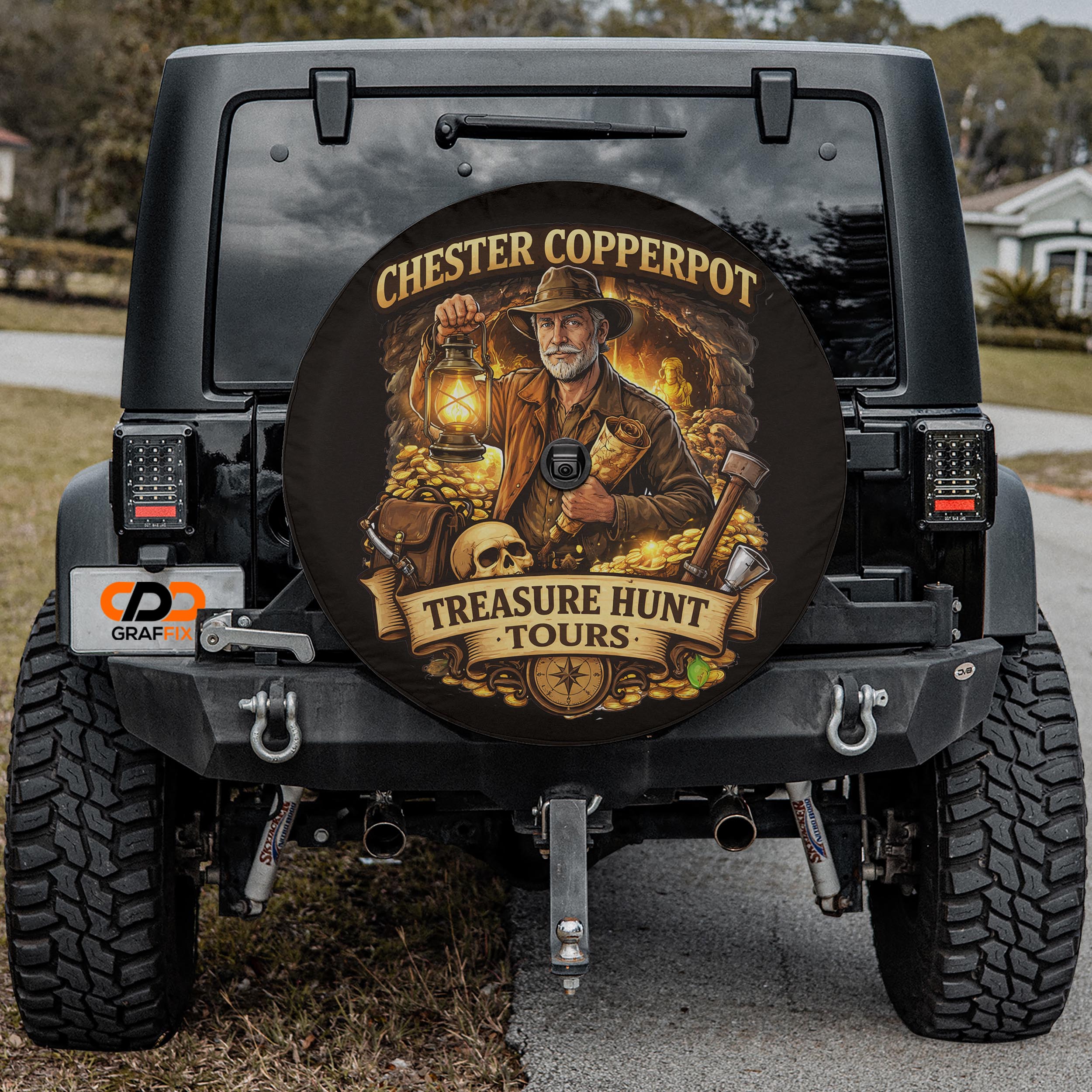 a black Jeep Wrangler with a large round spare tire cover on the rear of the vehicle. The cover has an illustration of a man in a safari hat and holding a lantern, surrounded by treasure chests and other safari-themed items.