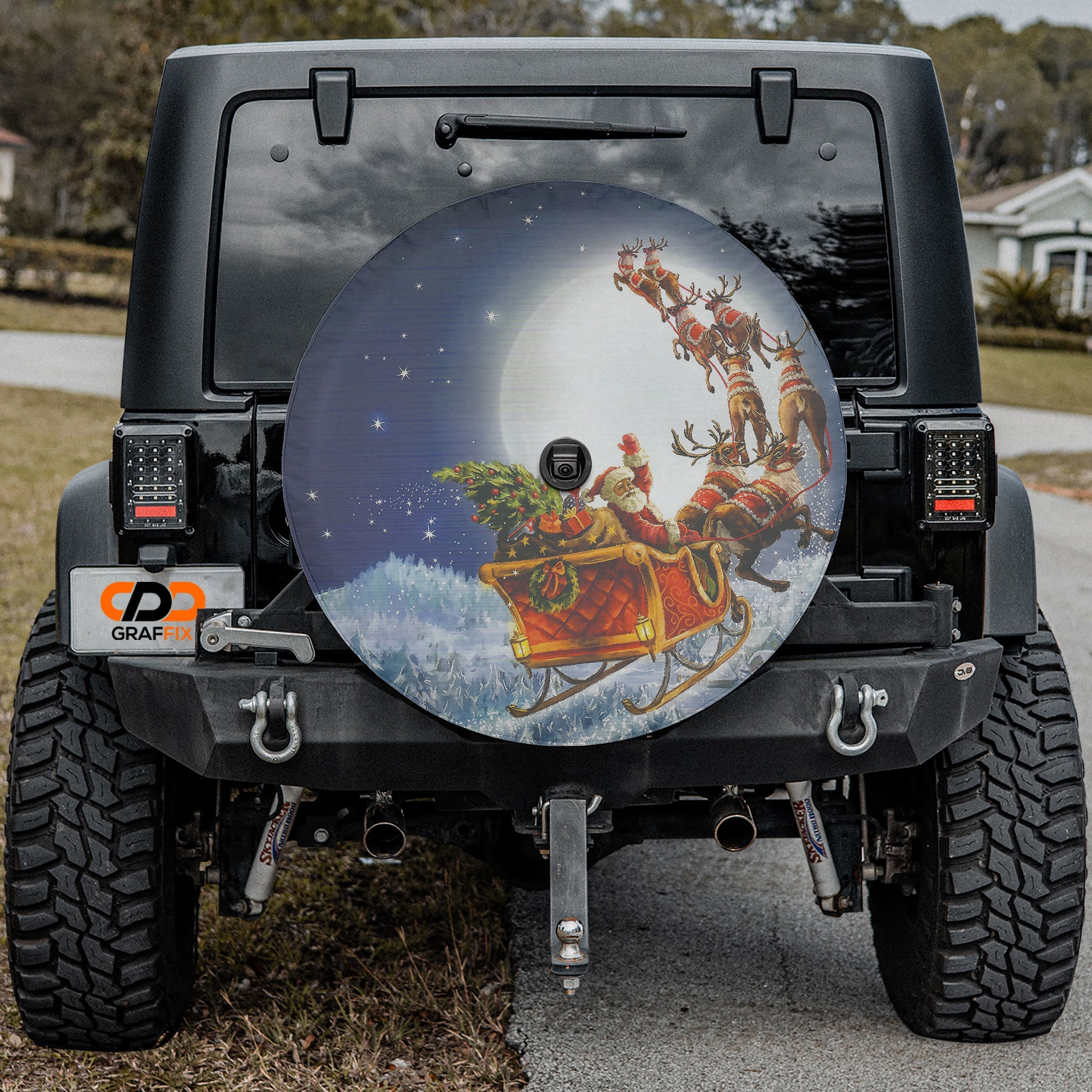 a black Jeep Wrangler with a large Christmas-themed spare tire on the rear.