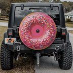 a black Jeep Wrangler with a large, colorful donut-shaped spare tire attached to the rear of the vehicle.