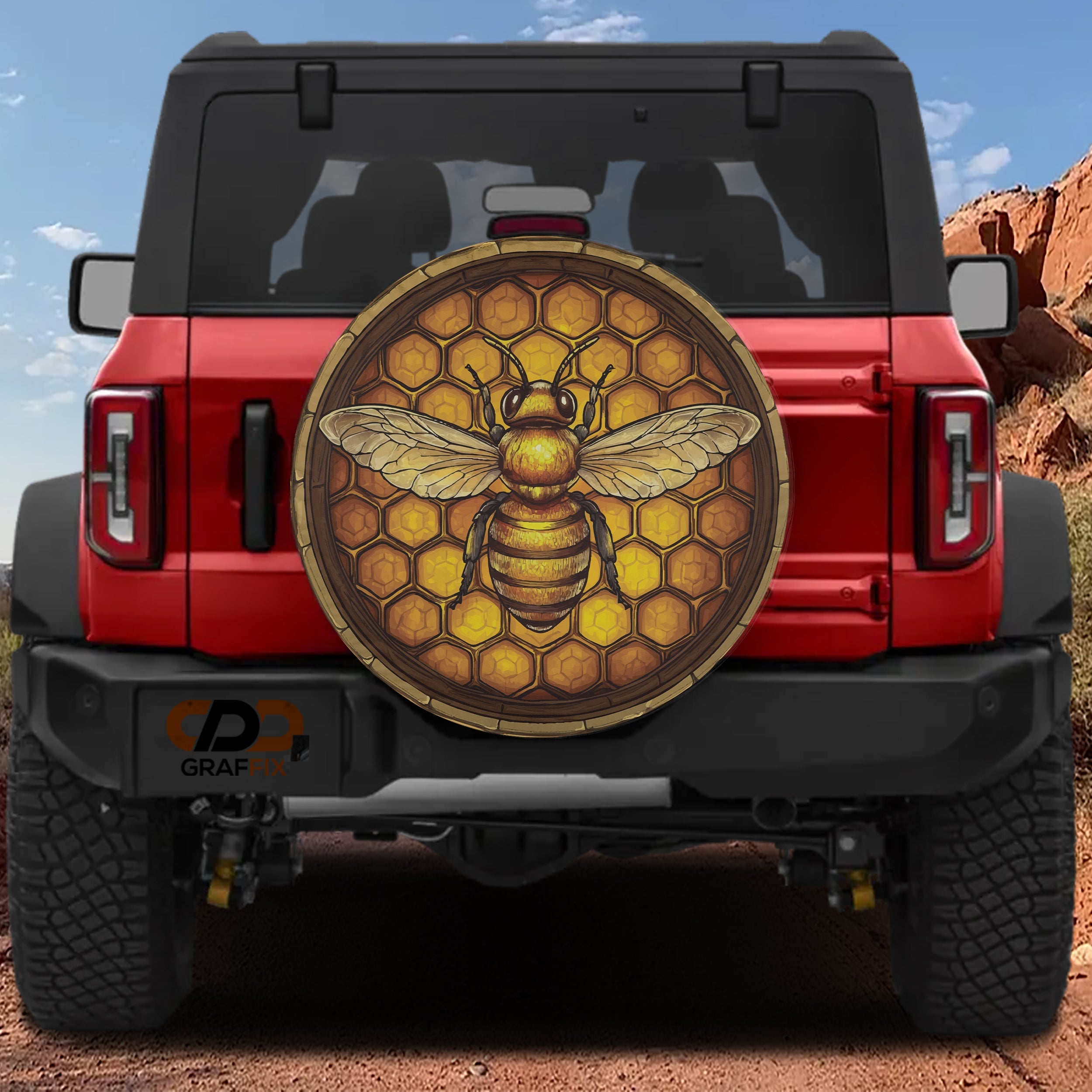 Honeycomb bee spare tire cover mounted on a red Bronco rear with golden hexagon pattern and detailed bee art