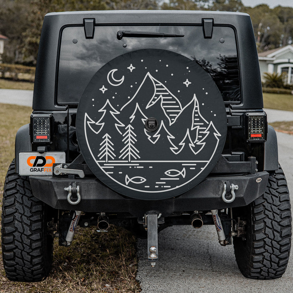 Midnight Pines spare tire cover with line-art pine forest scene mounted on Jeep Wrangler