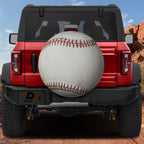 Baseball spare tire cover rear angle view on parked Jeep with backup camera cutout