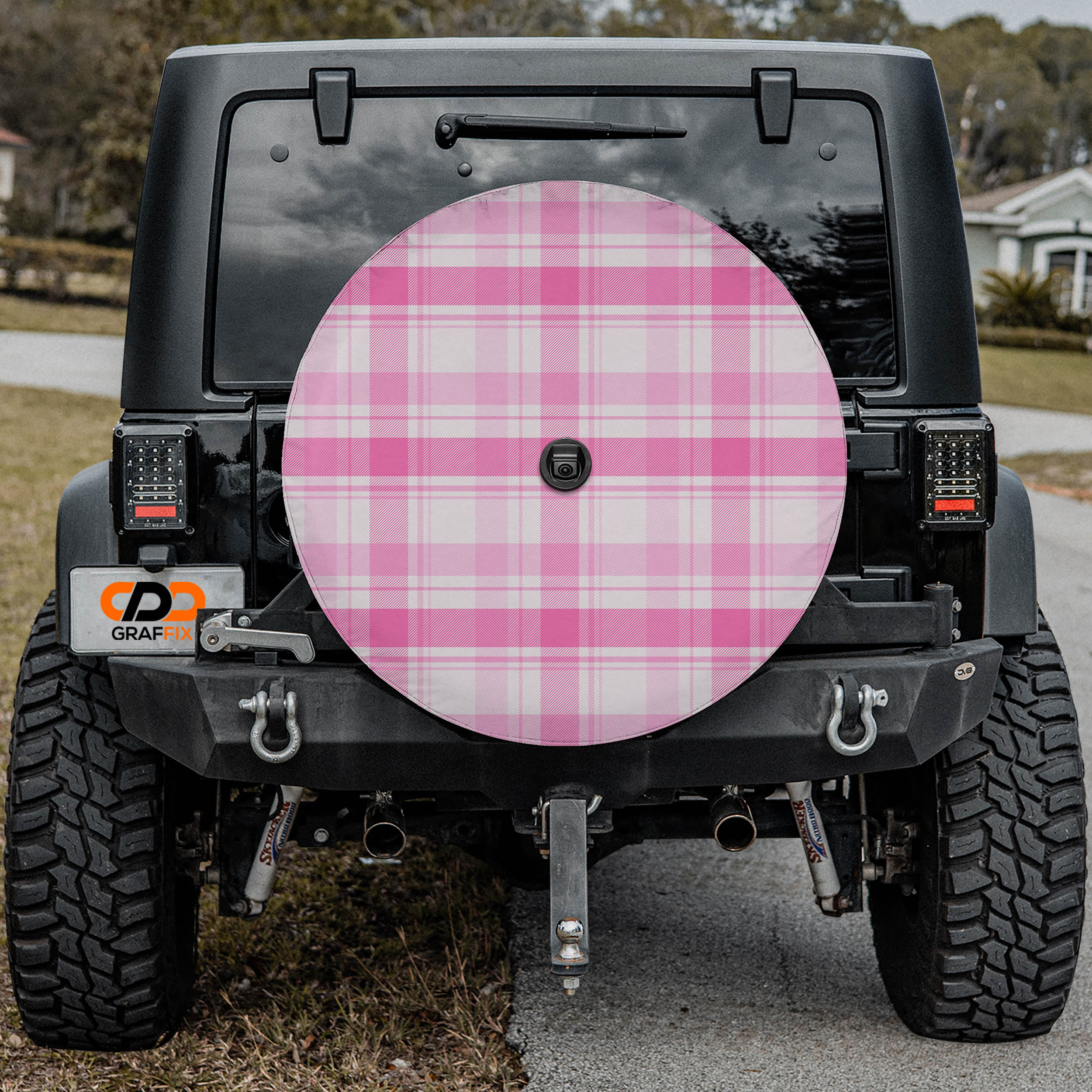 the rear of a black Jeep Wrangler with a large pink checkered wheel cover attached to it.