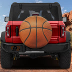 Basketball spare tire cover rear angle view on parked Jeep with backup camera cutout