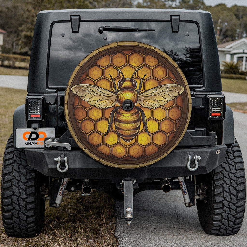 Honeycomb bee spare tire cover on a black Jeep rear with the golden hexagon and bee design outdoors
