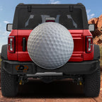 Golf ball spare tire cover rear angle view on parked Jeep with backup camera cutout