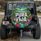 Pura Vida toucan macaw spare tire cover artwork mounted on black Jeep Wrangler in front yard scene