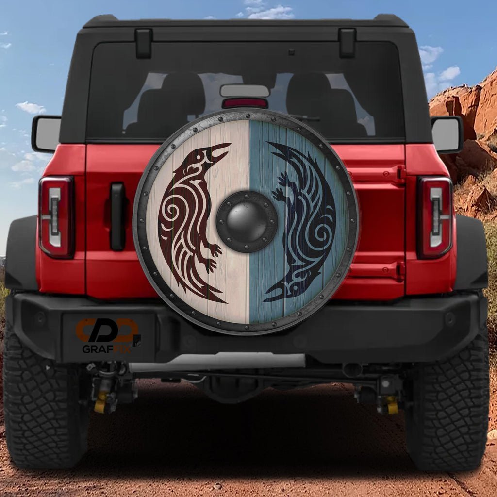 the back of a red Jeep Wrangler with a large, decorative wheel cover featuring a Viking-inspired design.