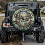 the back of a black Jeep Wrangler with a large circular decal on the rear window, featuring a forest scene with a full moon and stars.
