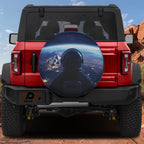 Space Station View spare tire cover with astronaut floating above Earth city lights cosmic dark backdrop
