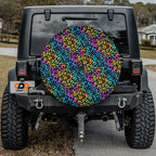Leopard rainbow print spare tire cover mounted on red Ford Bronco rear in desert setting
