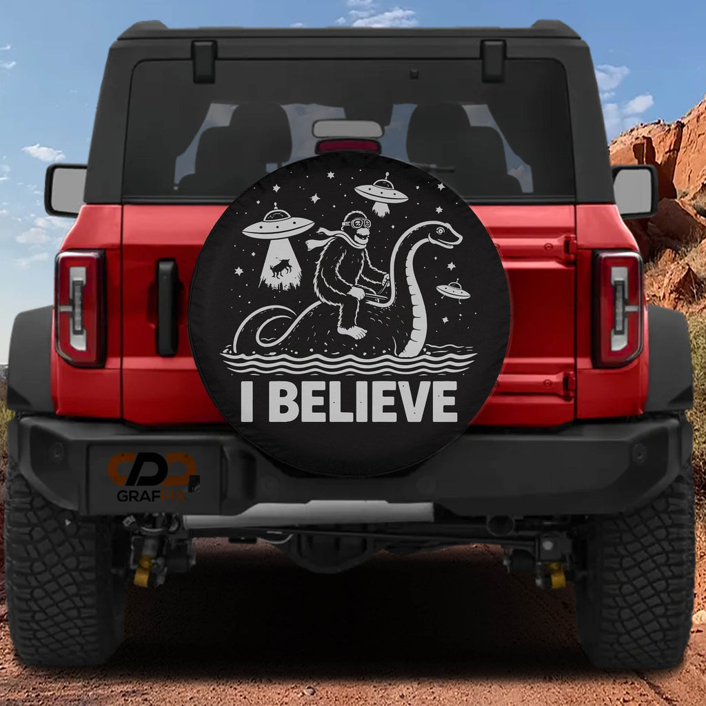 a red Jeep Wrangler with a large tire cover on the rear of the vehicle. The cover has a cartoon image of a person riding a giant snake and the text "I BELIEVE" written on it.