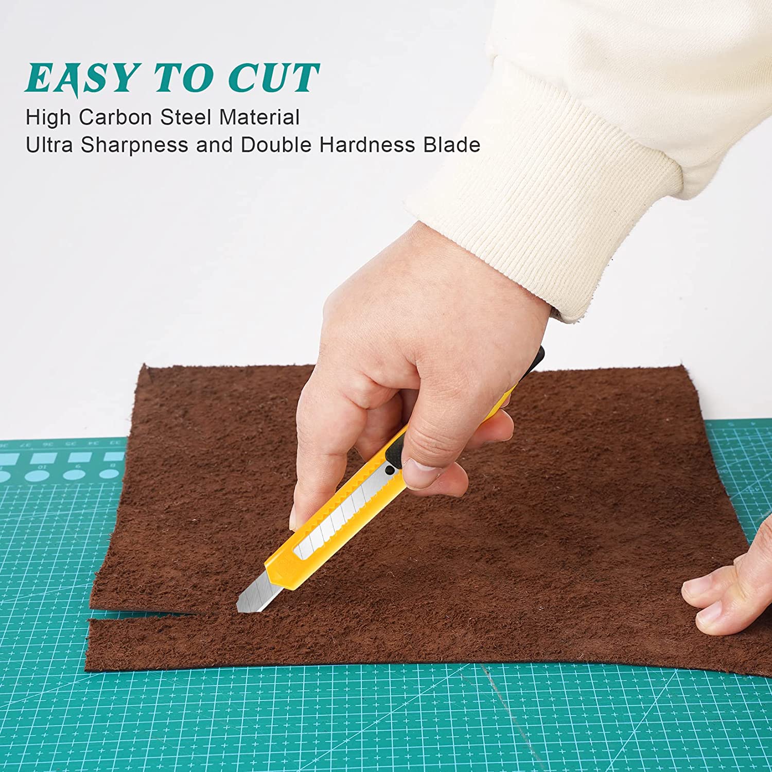 Yellow snap-off blade utility knife shown easily cutting through leather on a green self-healing cutting mat