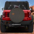 Topographic map tire cover on red Jeep Wrangler with orange contour lines and compass rose on charcoal fabric