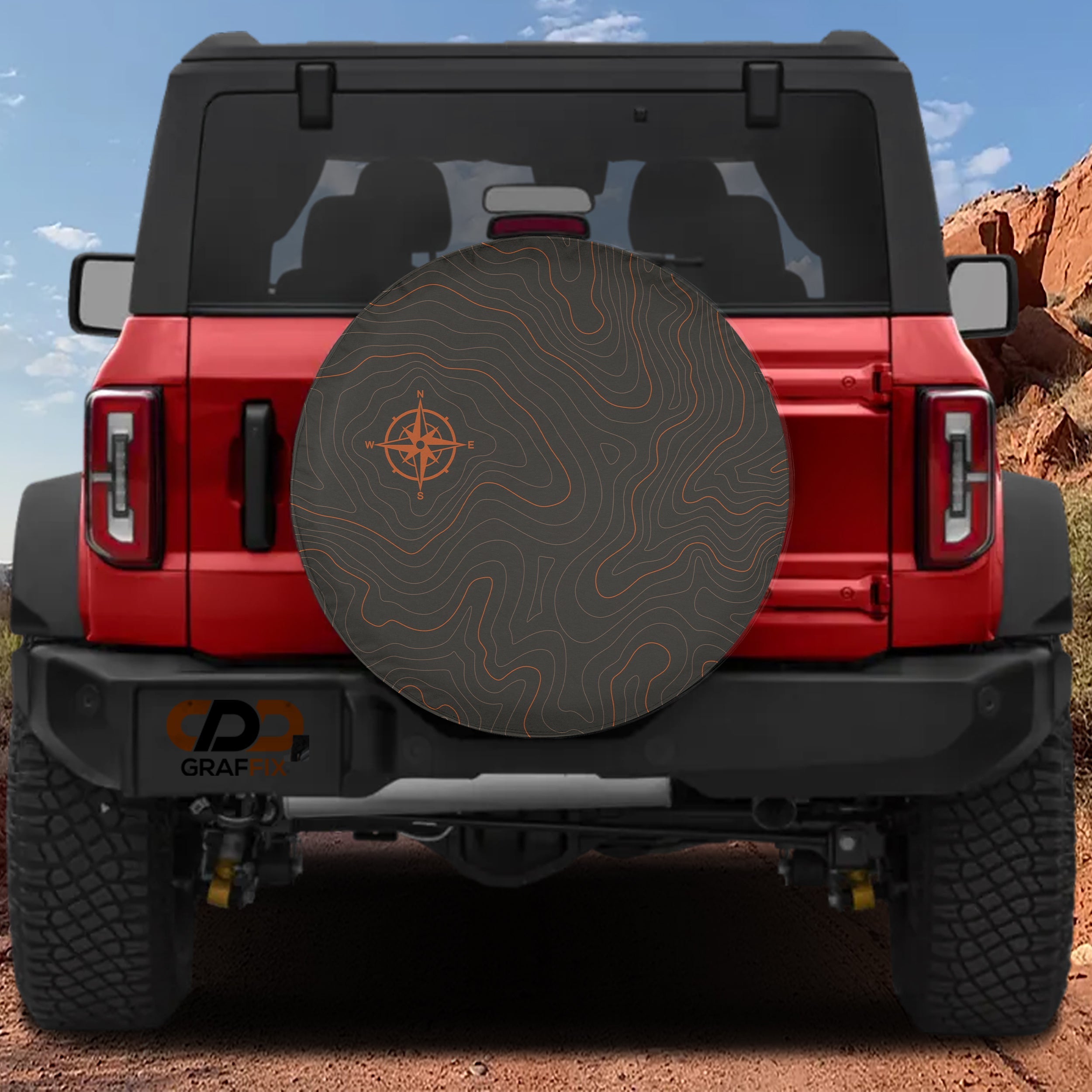 Topographic map tire cover on red Jeep Wrangler with orange contour lines and compass rose on charcoal fabric