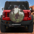 Bigfoot Sasquatch lurking in pine forest spare tire cover mounted on red Ford Bronco desert backdrop