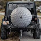 Golf ball white dimpled spare tire cover mounted on black Jeep Wrangler rear outdoors