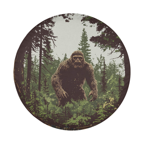 Round Bigfoot legend tire cover on white showing sasquatch silhouette evergreen pines vintage style