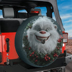 Cheerful yeti and holly spare tire cover displayed on the rear of a Jeep Wrangler with mountains