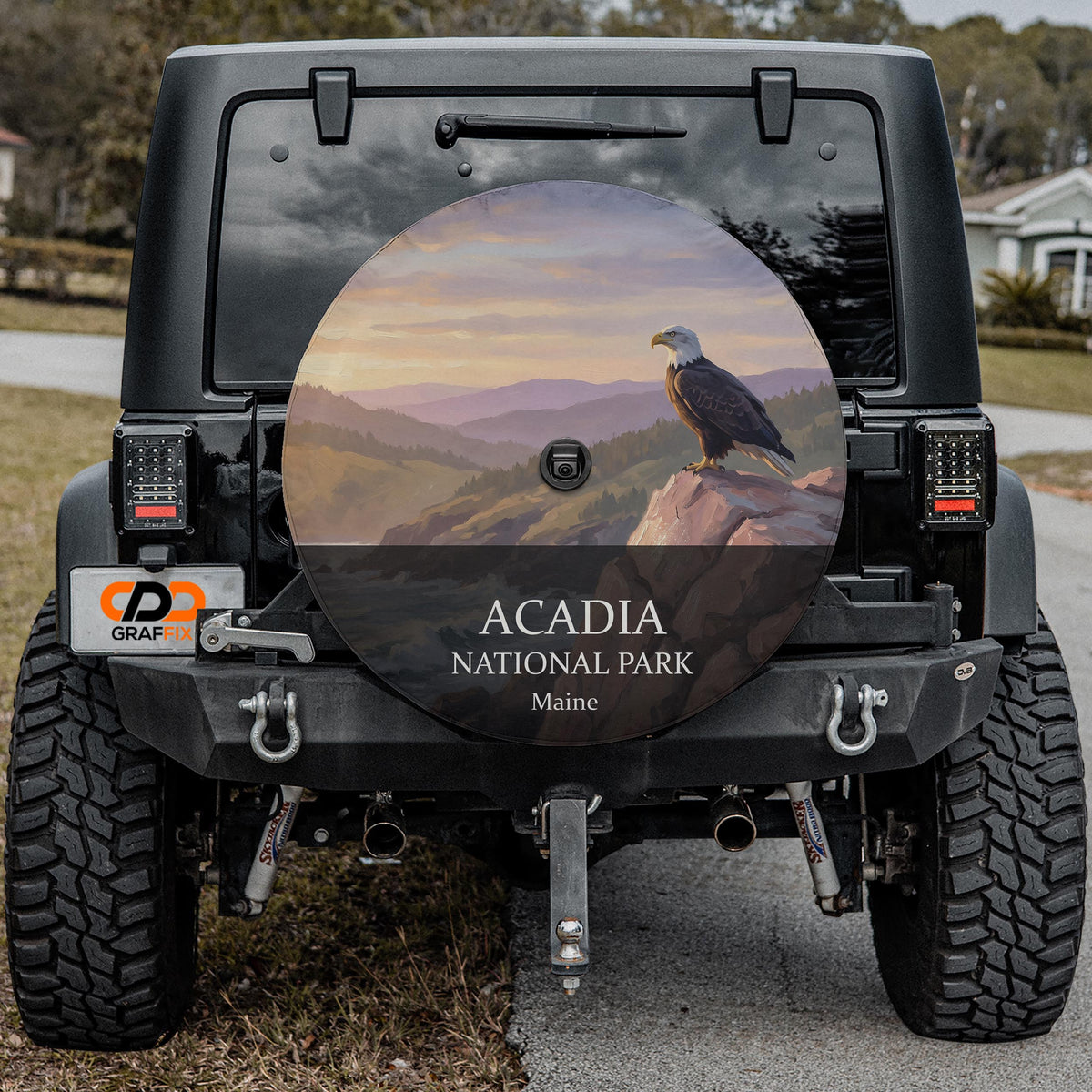 Acadia National Park spare tire cover on a black Jeep Wrangler parked in a driveway, backup camera port centered