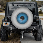 Eye On You spare tire cover mounted on a Jeep Wrangler rear wheel showing the iris design in driveway context