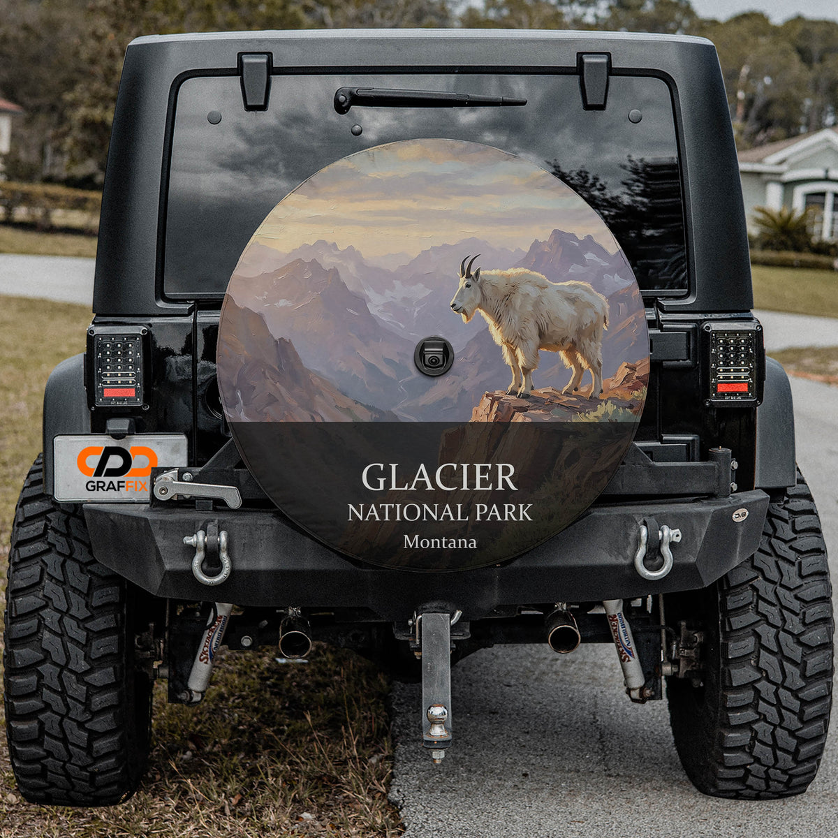 Glacier National Park spare tire cover on a Jeep Wrangler, showing a mountain goat on a ledge above glacier-carved peaks