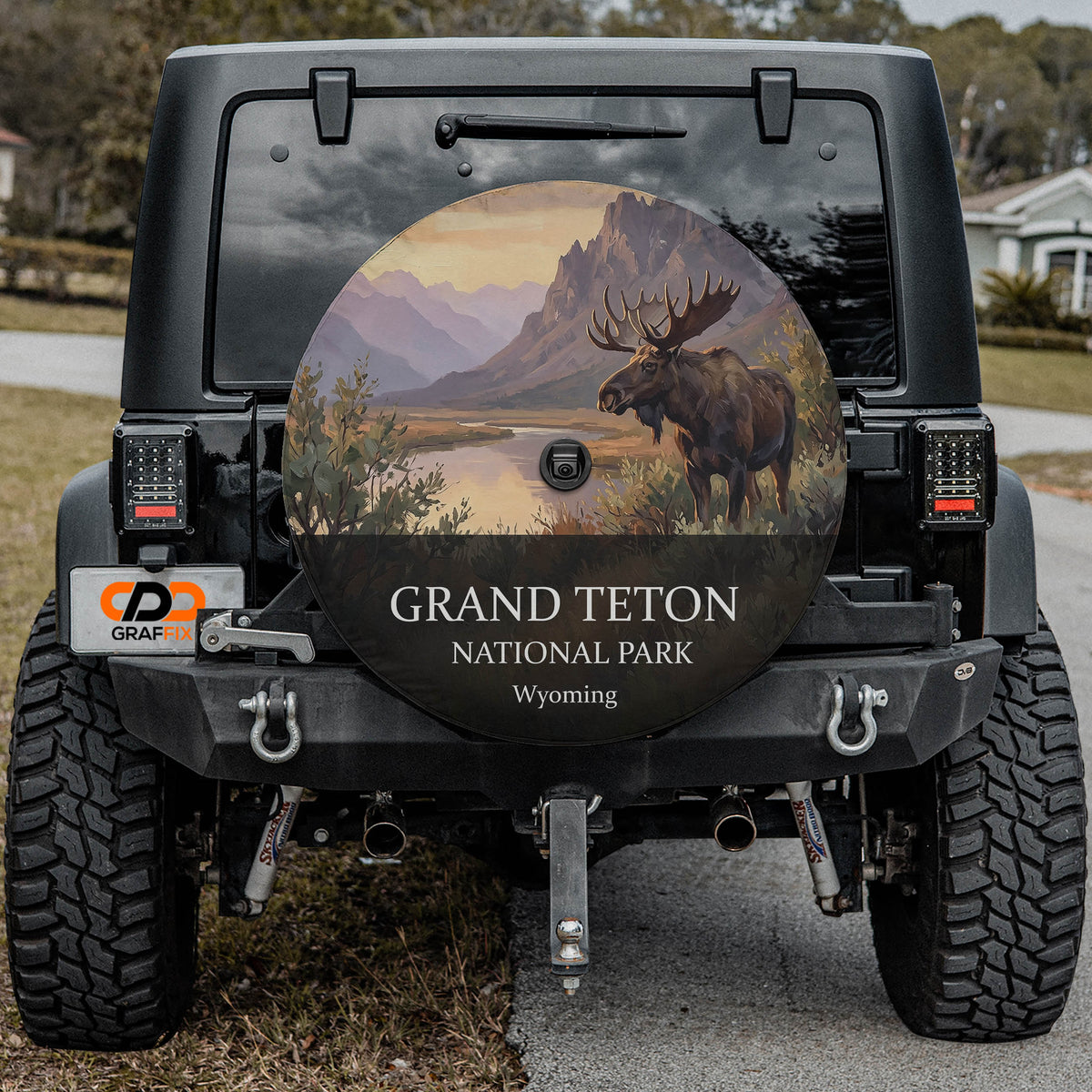 Grand Teton National Park spare tire cover on a Jeep Wrangler, showing a bull moose by a river below the Teton range