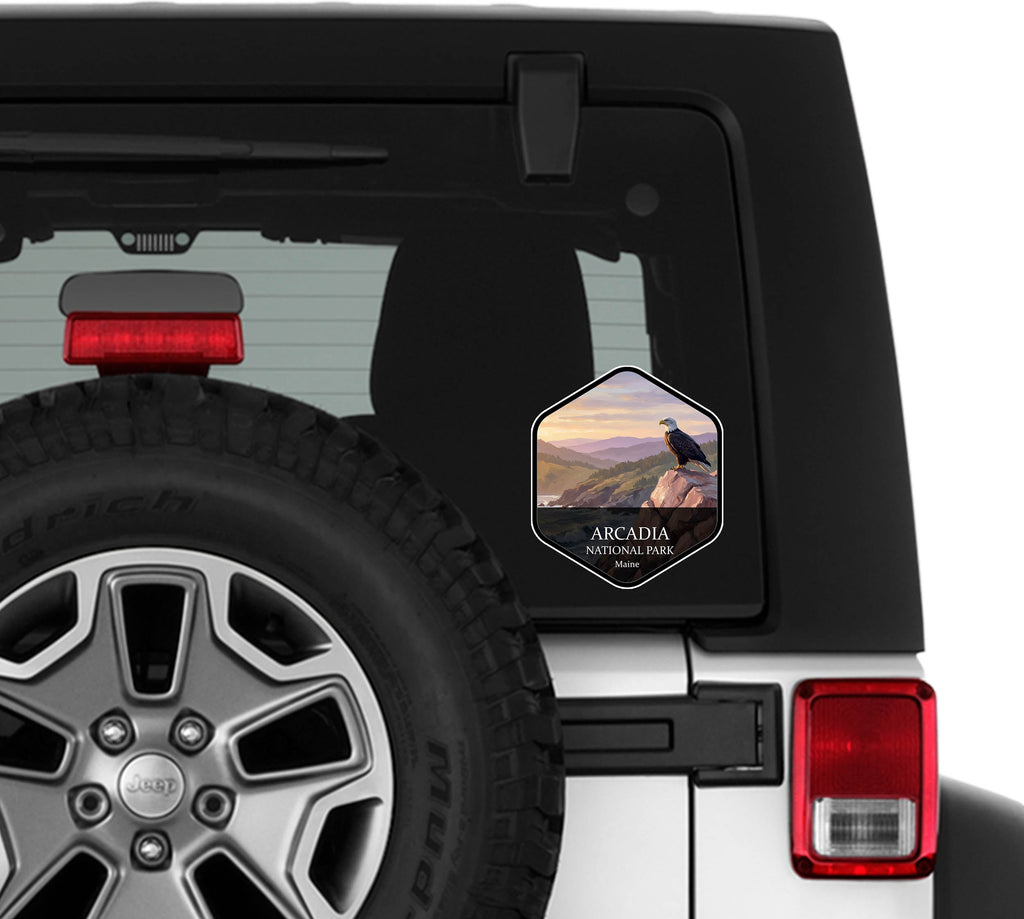 Acadia National Park badge sticker applied to the rear window of a white Jeep Wrangler beside the spare tire