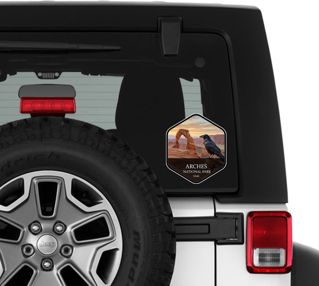 Arches National Park badge sticker applied to the rear window of a white Jeep Wrangler beside the spare tire