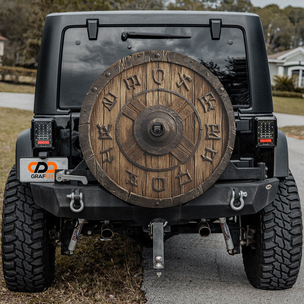 Viking wooden shield tire cover with carved runes mounted on the rear of a Jeep Wrangler tailgate