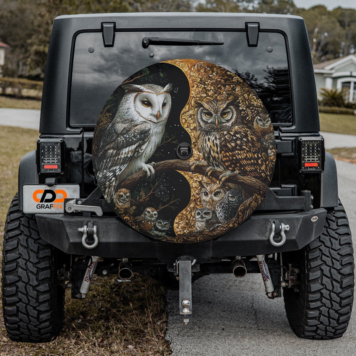 Yin-Yang Owls spare tire cover mounted on a Jeep Wrangler rear wheel with the mystical paired owls in soft light