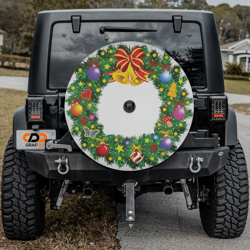 Black Jeep Wrangler showing Christmas wreath tire cover and GRAFFIX license plate on home driveway