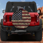 Rustic American flag spare tire cover mounted on red Ford Bronco rear with red rock canyon scenery