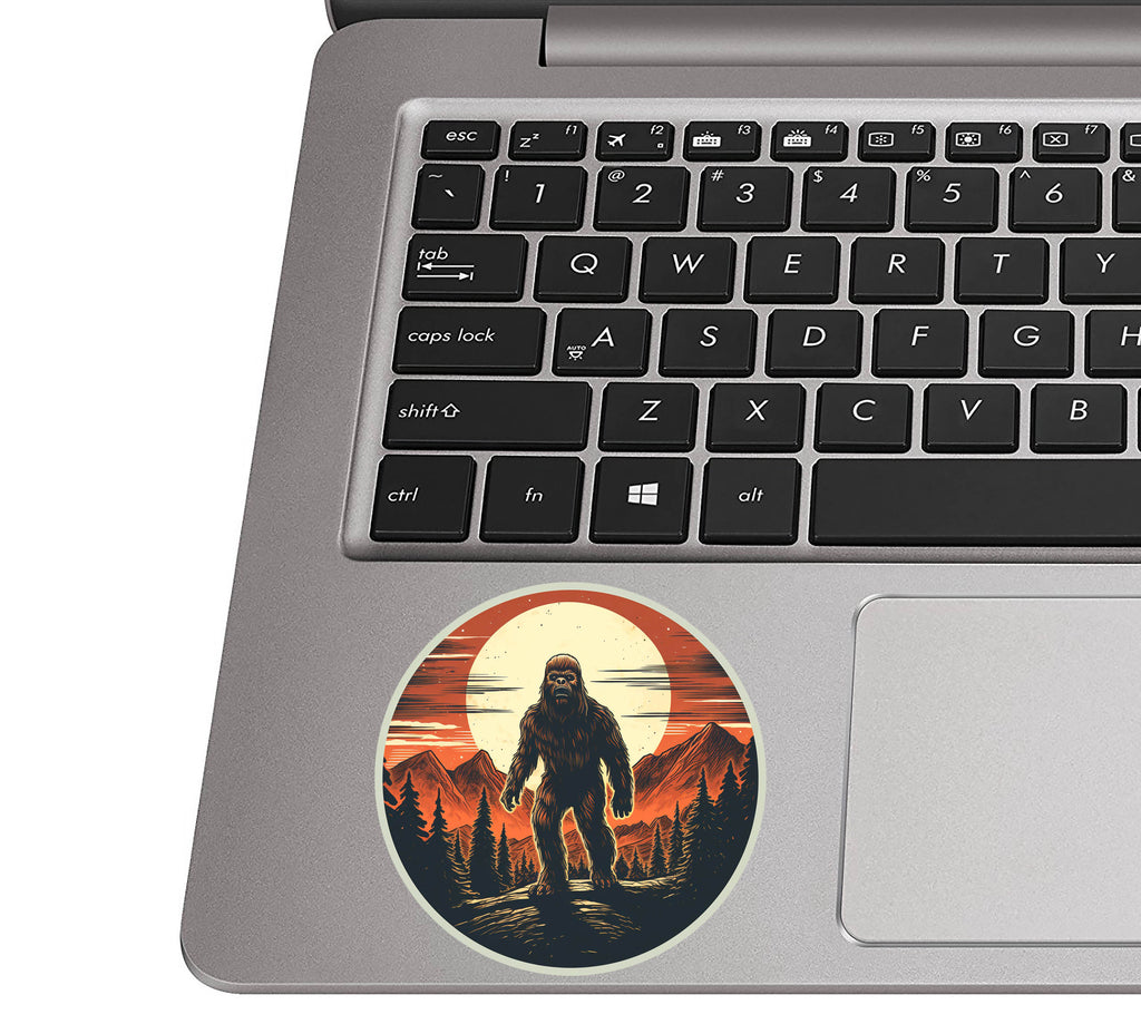 Bigfoot wilderness scene sticker on a silver laptop palm rest near a QWERTY keyboard to gauge actual size
