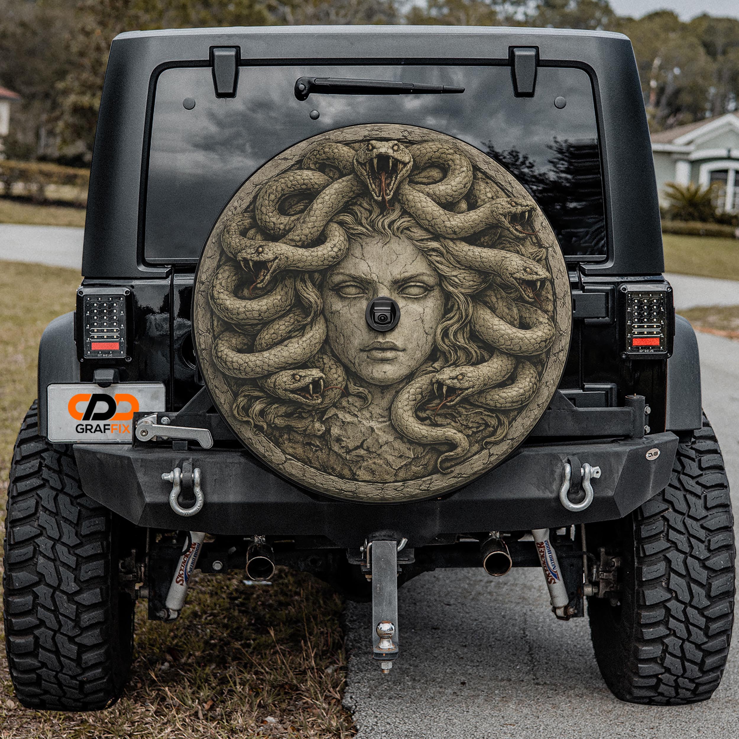 the back of a black Jeep Wrangler with a large, detailed stone carving of a woman's face on the rear window.
