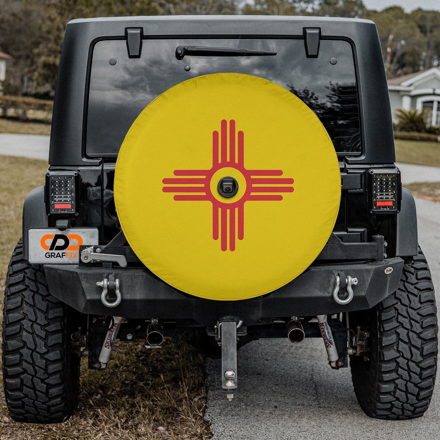 New Mexico State Flag spare tire cover on red Jeep Wrangler showing red Zia sun on yellow background